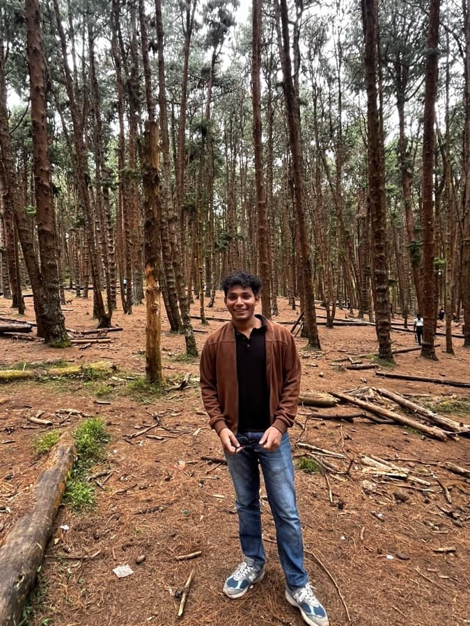 Ankit standing in a pine forest